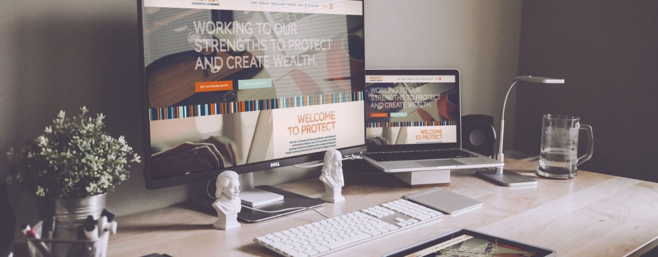 picture of a desk with a computer and iPad displaying the website by protect commercial