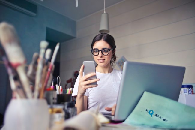 picture of a woman with glasses looking at her phone at her desk by protect commercial